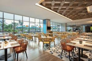 Hilton Garden Inn Sanya في سانيا: مطعم بطاولات وكراسي ونوافذ