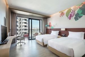 Hilton Garden Inn Sanya في سانيا: غرفة فندقية بسريرين وبلكونة