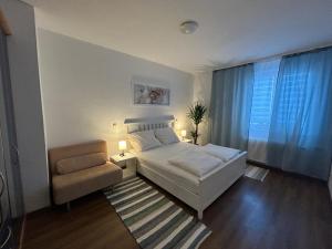 a bedroom with a white bed and a chair at SkyLineApartment in Frankfurt/Main