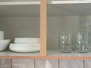 un estante con platos, tazones y vasos. en SkyLineApartment, en Frankfurt