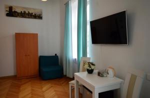 a living room with a television and a blue chair at CENTRAL WAWEL Apartments in Krakow