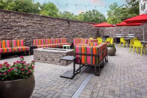 ソールズベリーにあるHome2 Suites By Hilton Salisburyのレンガの壁、カラフルな椅子とテーブル付きのパティオ