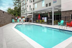 a swimming pool with chairs and a building at Home2 Suites By Hilton Salisbury in Salisbury