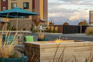 a table with an umbrella and chairs with mountains in the background at Hampton Inn West Valley Salt Lake City in West Valley City