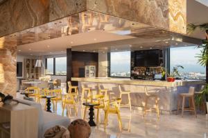 a restaurant with a bar with yellow chairs at Homewood Suites By Hilton Santo Domingo in Santo Domingo
