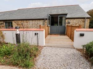 a cottage with a wooden walkway leading to a door at Carines Barns - Pol in Newquay