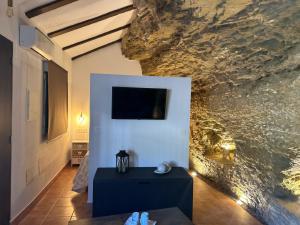 una sala de estar con una pared de piedra y una mesa. en Casa Cueva Sol y Luna Setenil, en Setenil