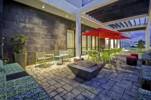 un patio con mesas, sillas y una sombrilla roja en Home2 Suites By Hilton Shreveport, en Shreveport