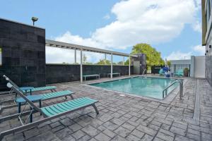 - une piscine avec 2 chaises longues à côté d'un bâtiment dans l'établissement Home2 Suites By Hilton Shreveport, à Shreveport