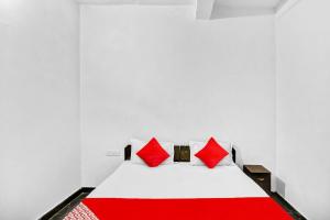 łóżko z czerwonymi poduszkami w białym pokoju w obiekcie OYO Flagship 81043 Paradise Inn w mieście Panchli