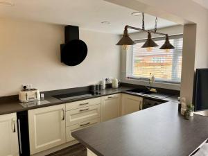 cocina con armarios blancos y encimera negra en Comfortable ground floor, 2 BR modern Apartment en Broadheath