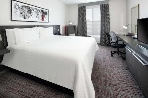 Cette chambre comprend un grand lit blanc et un bureau. dans l'établissement Hilton Garden Inn Irvine Spectrum Lake Forest, à Lake Forest