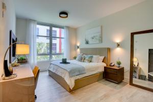 a bedroom with a bed and a desk and a mirror at New! Beach Access with Rooftop Pool in Hollywood