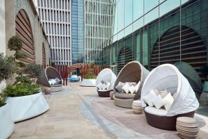 une rangée de chaises blanches assises à côté d'un bâtiment dans l'établissement Hilton Garden Inn Kuwait, à Koweït