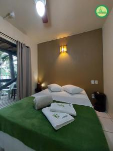 a bedroom with a large bed with towels on it at Pousada Arthemis in Garopaba