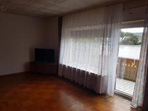 a living room with a window and a television at Pension Ehringshausen in Ehringshausen