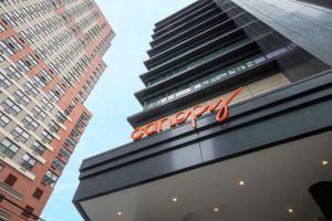 um sinal na lateral de um edifício com dois edifícios altos em Canopy By Hilton Jersey City Arts District em Jersey City