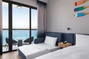 a hotel room with two beds and a view of the ocean at Hampton by Hilton Marjan Island in Ras al Khaimah