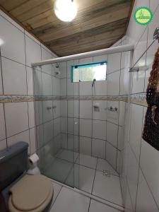 a bathroom with a toilet and a glass shower at Pousada Arthemis in Garopaba