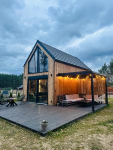 Casa de madera grande con terraza y sofá en Bliżej Lasu, en Śliwice