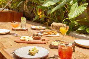 einen Holztisch mit Teller mit Speisen und Getränken in der Unterkunft Canopy By Hilton Sao Paulo Jardins in São Paulo