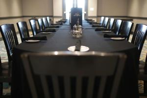 - une longue table dans une pièce avec des tables et des chaises noires dans l'établissement The Rewind West Des Moines, Tapestry Collection By Hilton, à West Des Moines