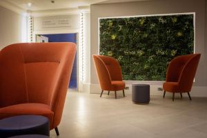 una sala d'attesa con sedie arancioni e una grande finestra di DoubleTree by Hilton London Elstree a Borehamwood