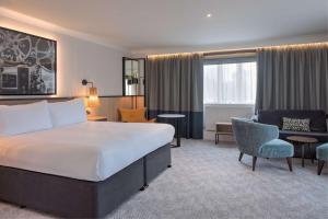 博勒姆伍德DoubleTree by Hilton London Elstree的一间带床和椅子的酒店房间