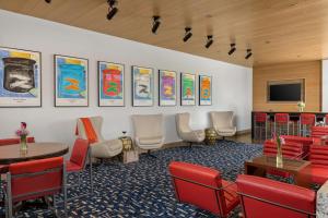 una sala de estar con sillas, mesas y TV de pantalla plana. en The Art Hotel Denver, Curio Collection by Hilton en Denver