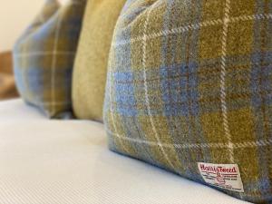 a couch with a plaid pillow with a sticker on it at Kinnoull House near Stornoway Hot Tub/Pet Friendly in Garrabost