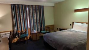 um quarto de hotel com uma cama e cadeiras e uma janela em Mariner motor hotel em Collingwood