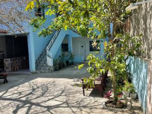 a blue building with a tree in a courtyard at SUITEs E FLATs MONTE ALTO ARRAIAL DO CABO in Arraial do Cabo