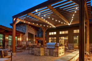 an outdoor kitchen with a wooden pergola with lights at Homewood Suites By Hilton Eagle Boise, Id in Eagle