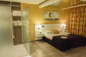 Schlafzimmer mit einem Bett und einer Glasdusche in der Unterkunft Hotel el Secreto in Comodoro Rivadavia