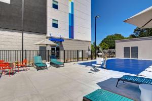 a patio with chairs and a table and a pool at Tru By Hilton Rocky Mount, Nc in Rocky Mount