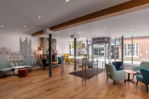 uma sala de estar com cadeiras, uma mesa e janelas em Hampton by Hilton Canterbury em Canterbury