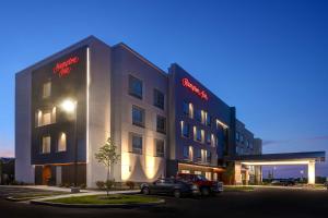 a building with a car parked in a parking lot at Hampton Inn Crown Point, In in Crown Point