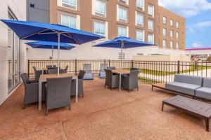 patio ze stołami, krzesłami i niebieskimi parasolami w obiekcie Hampton Inn & Suites Bloomfield Hills Detroit w mieście Bloomfield Hills