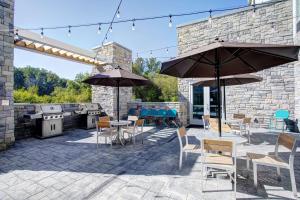 an outdoor patio with tables and chairs and umbrellas at Home2 Suites By Hilton Johnson City, Tn in Johnson City