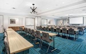 Home2 Suites By Hilton Johnson City, Tn في جونسون سيتي: قاعة اجتماعات مع طاولات وكراسي وشاشة عرض