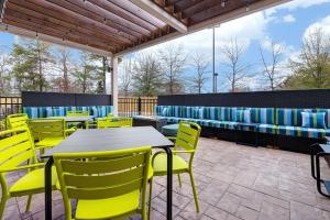 a patio with yellow chairs and tables and a bench at Home2 Suites By Hilton Blythewood, Sc in Blythewood