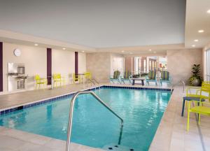 una piscina en una habitación de hotel con sillas y mesas en Home2 Suites By Hilton Tupelo en Tupelo