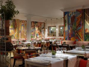 a restaurant with tables and chairs and paintings on the walls at Charlotte Street Hotel, Firmdale Hotels in London