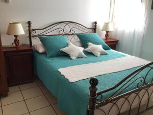 una camera da letto con letto con lenzuola e cuscini blu di Les Capucines a Saint-Pierre