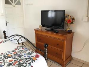 une télévision posée sur une commode avec un lit dans l'établissement Les Capucines, à Saint-Pierre