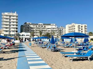 una spiaggia con sedie a sdraio e ombrelloni blu di Yes Hotel Touring & SPA a Rimini