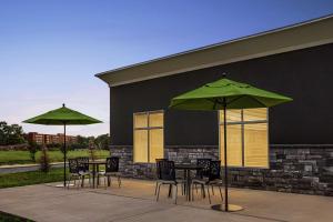 eine Terrasse mit Tischen, Stühlen und grünen Sonnenschirmen in der Unterkunft Homewood Suites By Hilton Carlisle in Carlisle