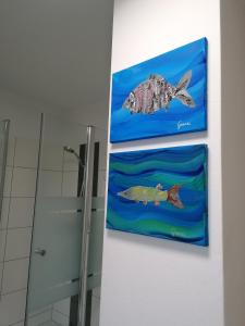 zwei Gemälde von Fischen an der Wand eines Badezimmers in der Unterkunft Apartment Anna im Mostviertel in Seitenstetten Markt