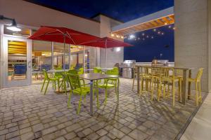 a restaurant with tables and chairs and red umbrellas at Home2 Suites By Hilton Wilkes-Barre in Wilkes-Barre