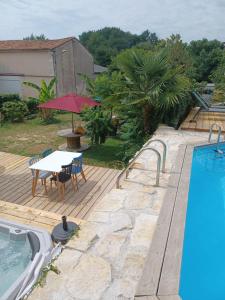 um deque de madeira com uma mesa e cadeiras ao lado de uma piscina em Nid Charentais Angouleme pool jacuzzi em La Poterie